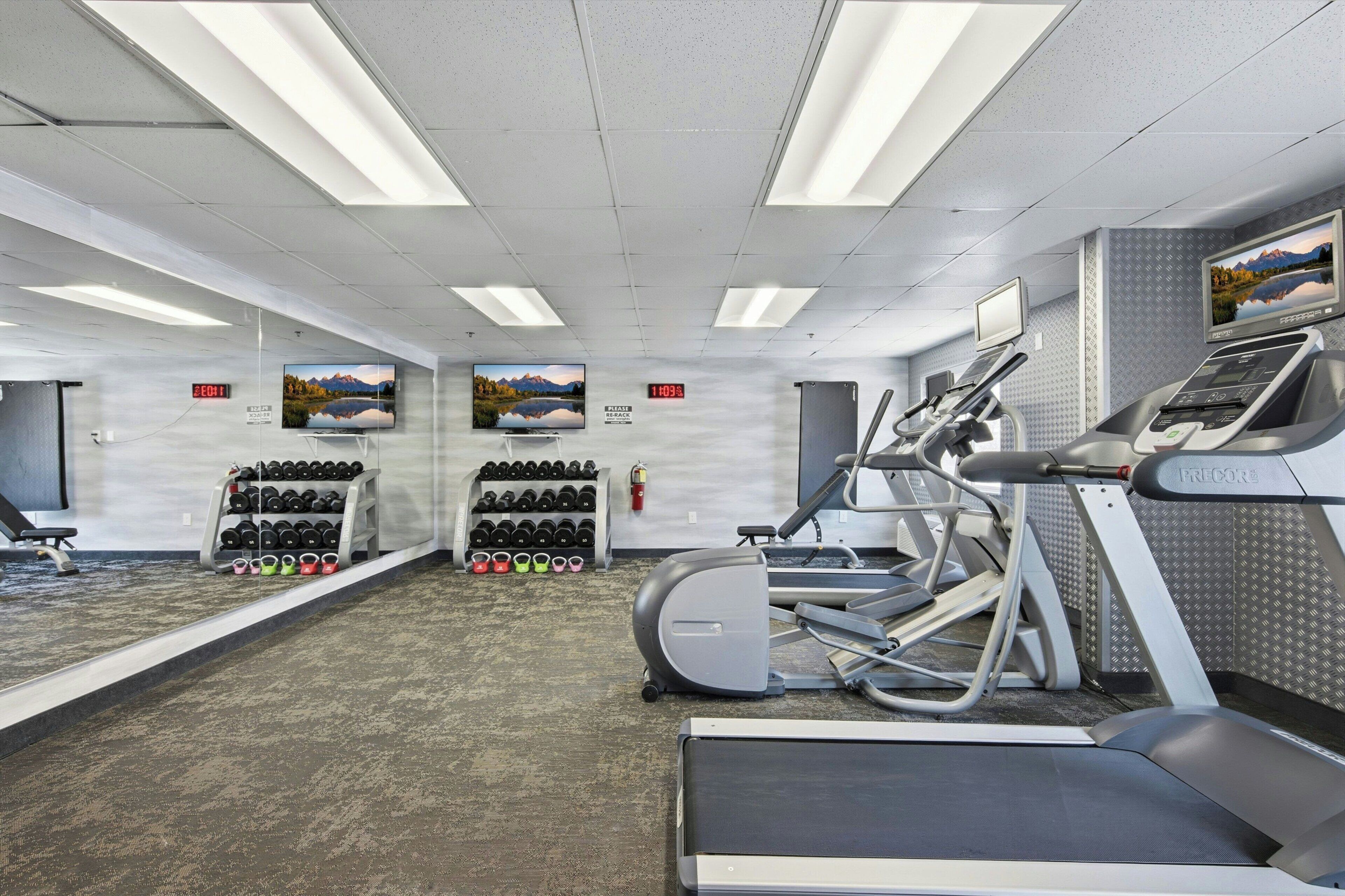 A gym with treadmills, an elliptical, and a wall-mounted TV.