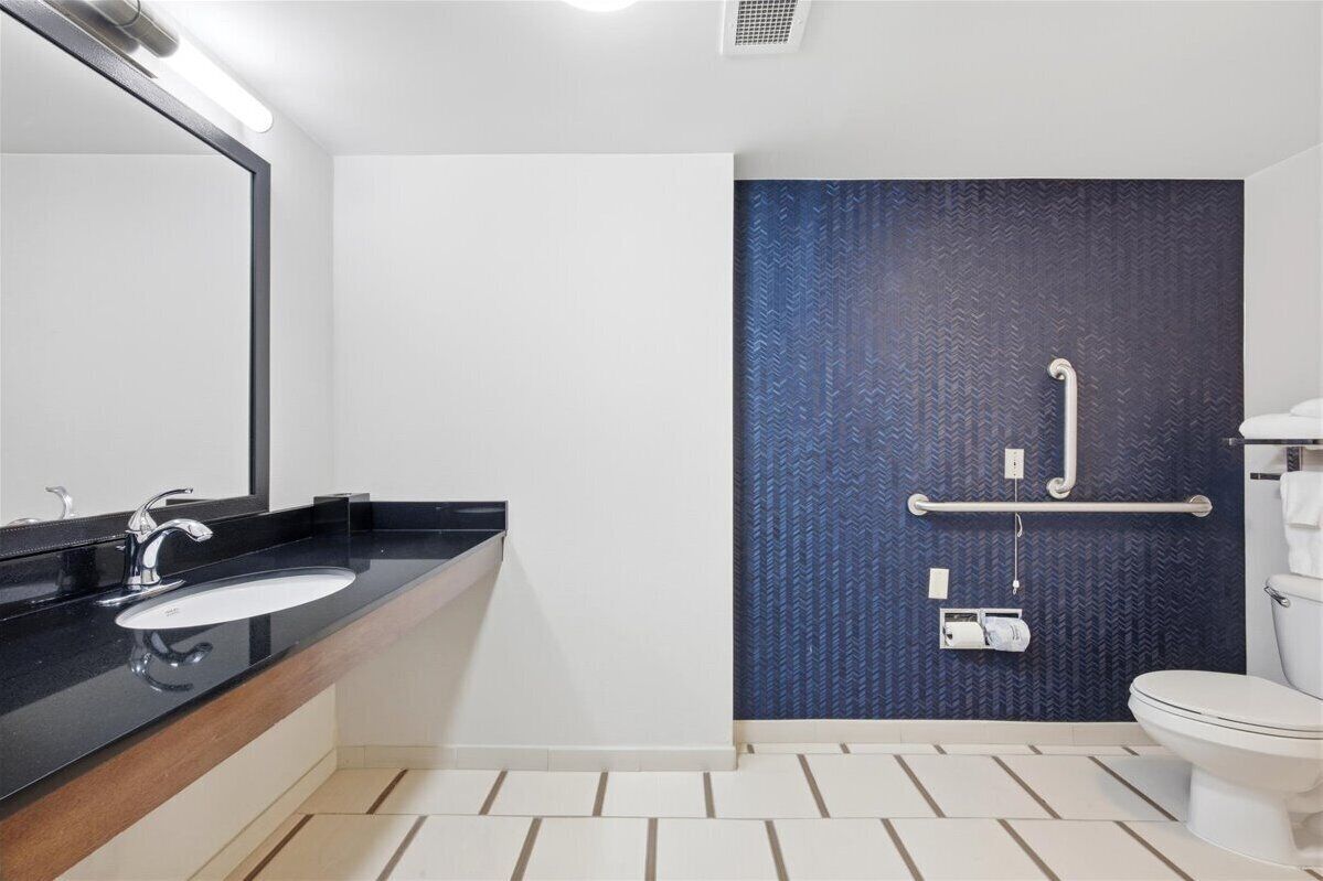 A modern bathroom with a black sink, white toilet, and a blue textured wall.