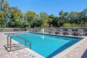 Una piscina al aire libre, sombrillas, sillones reclinables de piscina