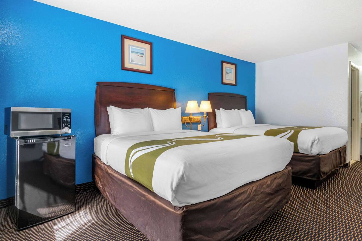 A hotel room with two beds, a microwave, and a refrigerator.