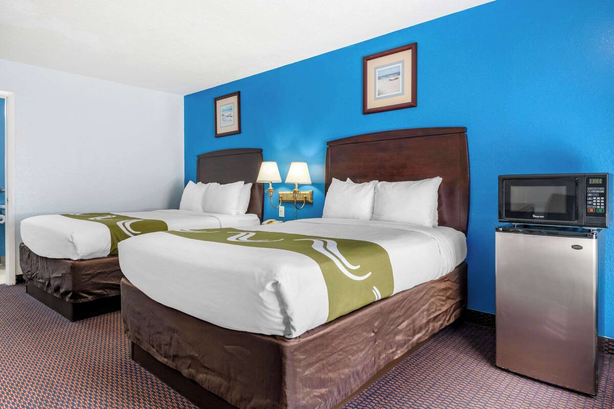 A hotel room with two beds, a refrigerator, and a microwave.