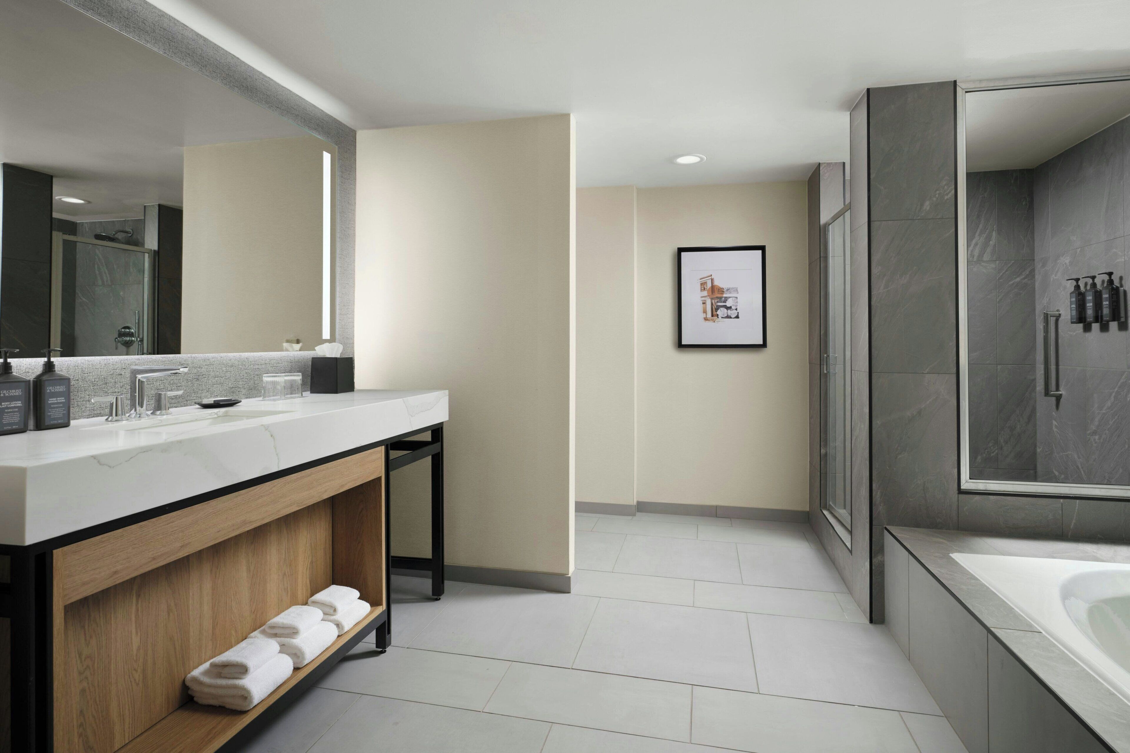 A modern bathroom with a large mirror, a vanity with a sink, and a shower area.