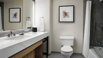 Une salle de bain moderne avec un lavabo blanc, des toilettes et une douche. Des tableaux encadrés ornent le mur.