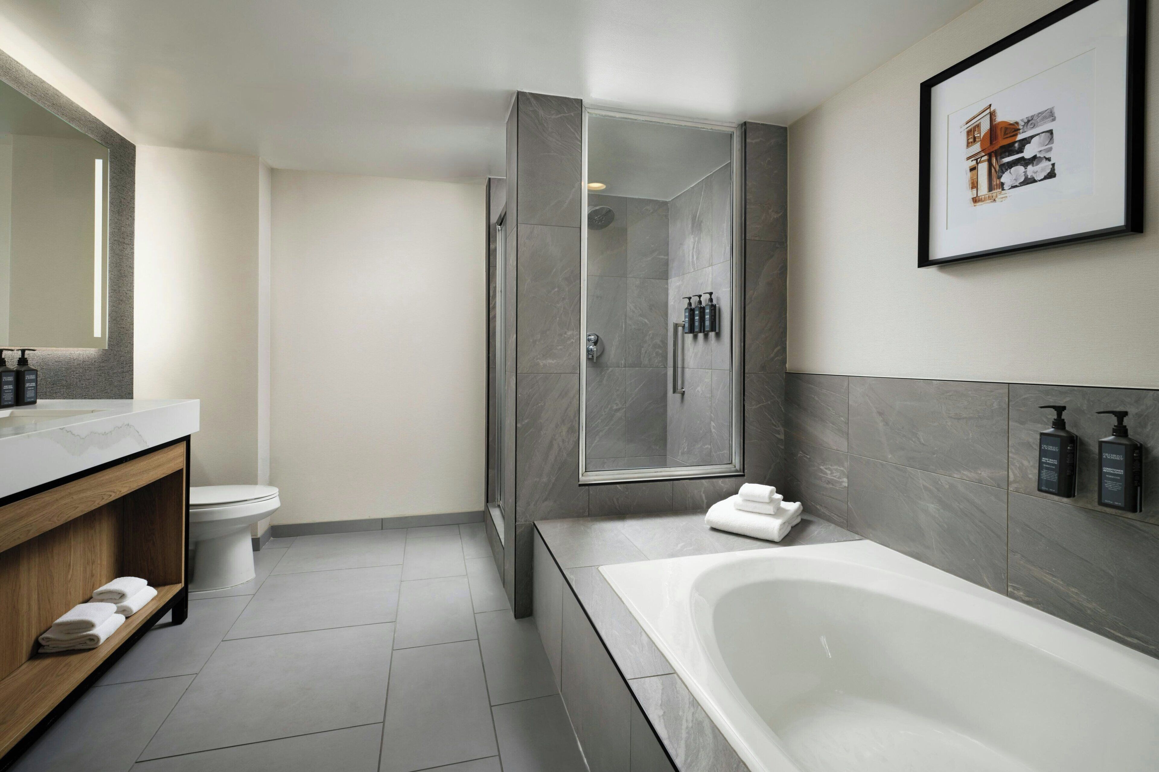 A modern bathroom with a large bathtub, a shower enclosure, and a vanity with a mirror.