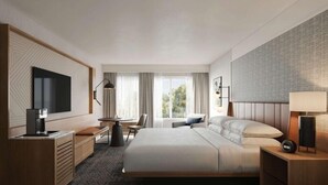 A modern hotel room with a large bed, a desk, a chair, a TV, and a window with curtains.
