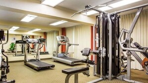 Een sportschool met loopbanden, krachtapparaten en een bank.