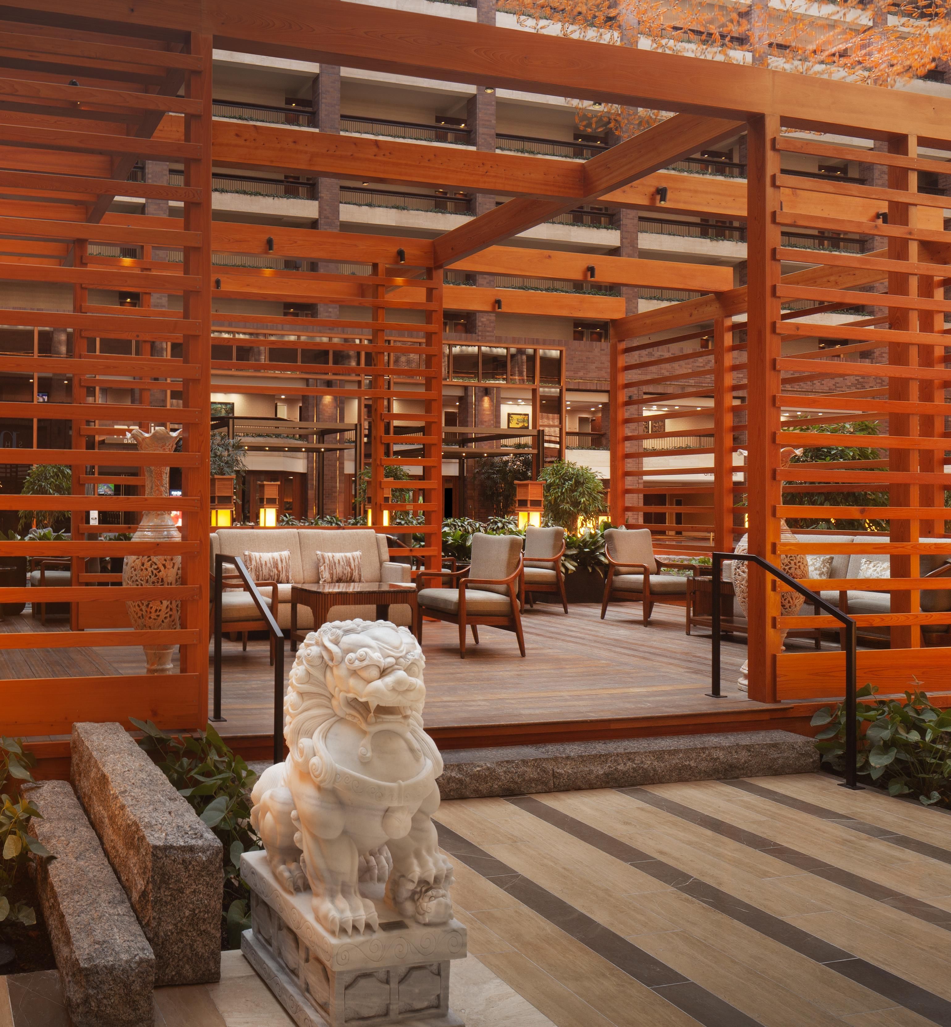 A wooden pergola structure with seating and a decorative lion statue in the foreground.