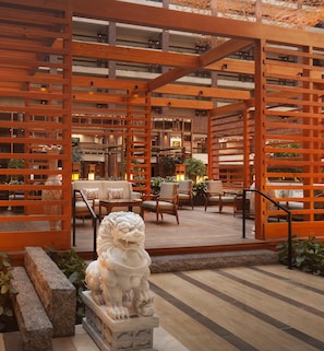 Una estructura de pérgola de madera con asientos y una estatua decorativa de león al frente.