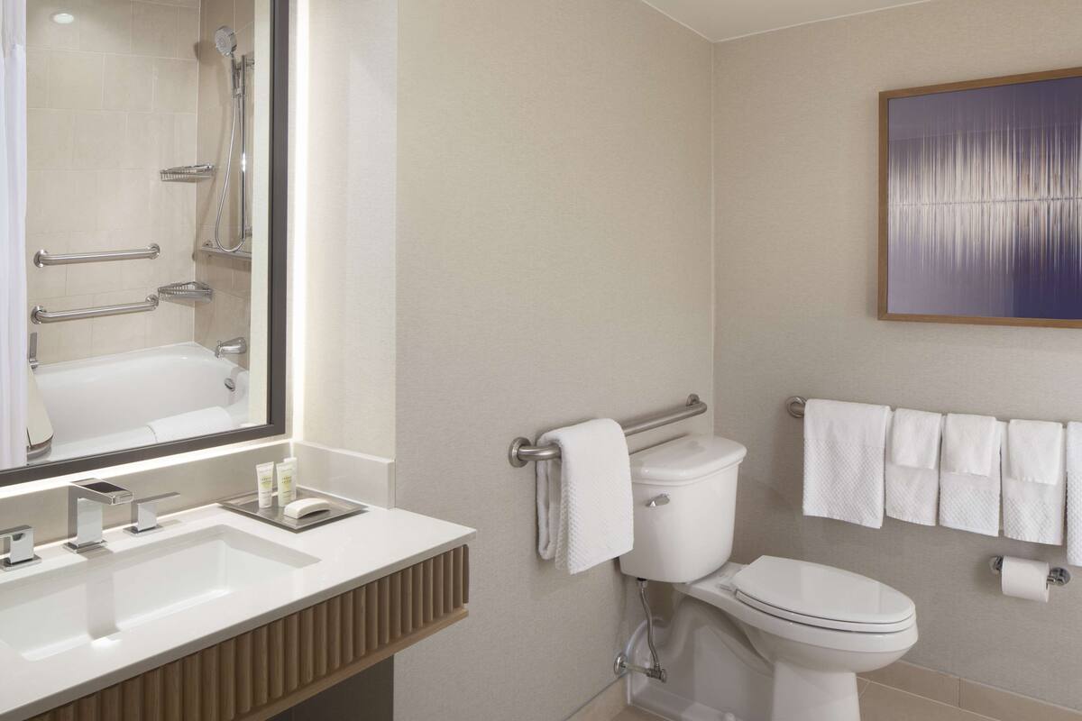 A modern bathroom with a large mirror, a sink, a toilet, and a shower.
