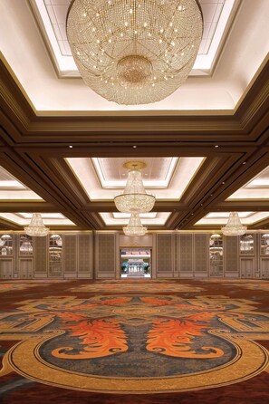 A grand hall with a large chandelier, ornate carpet, and a high ceiling with skylights.