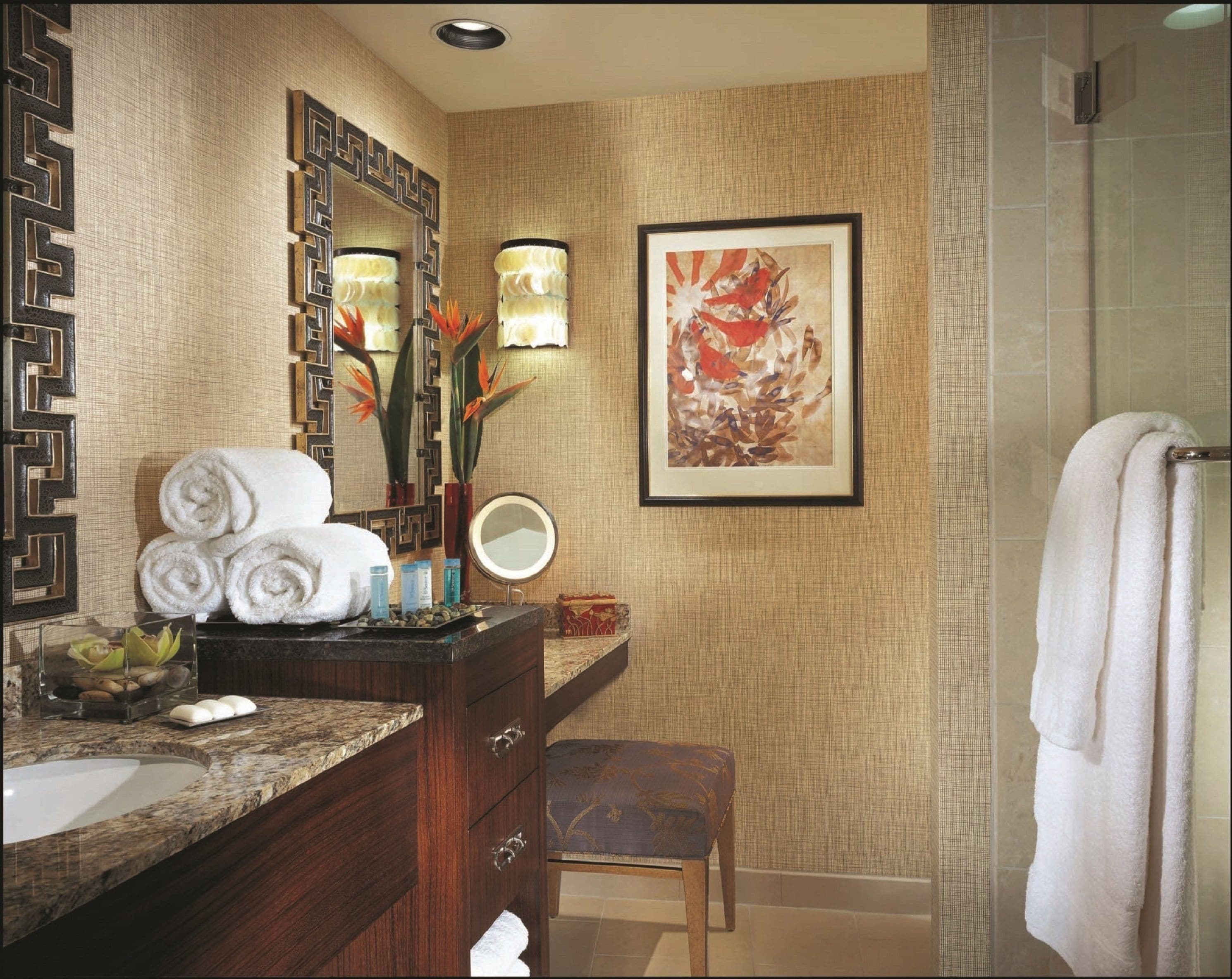 Une salle de bain avec un lavabo en marbre, un miroir, une œuvre d’art encadrée et un porte-serviettes.