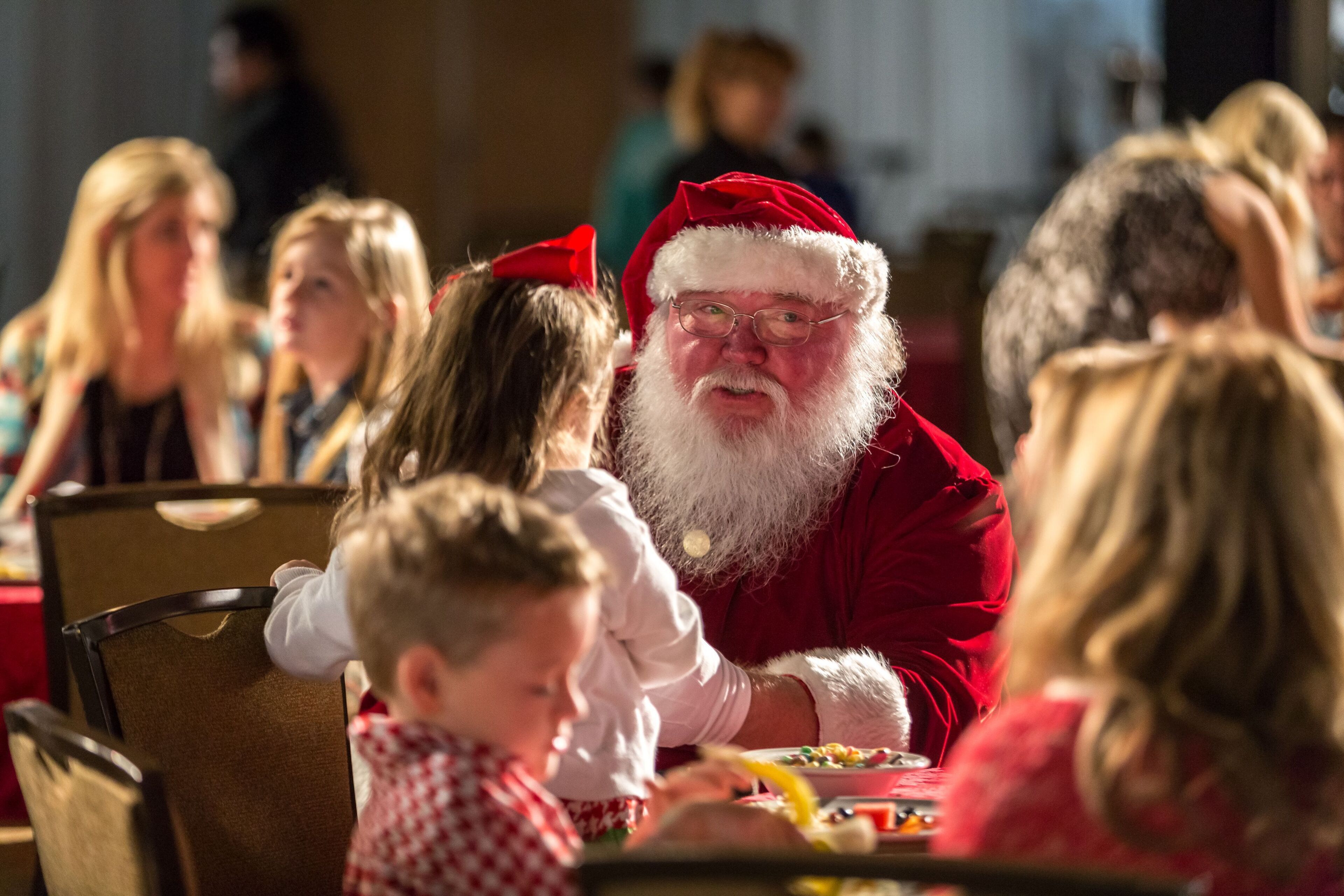 A person in a red costume seated at a table with a child.