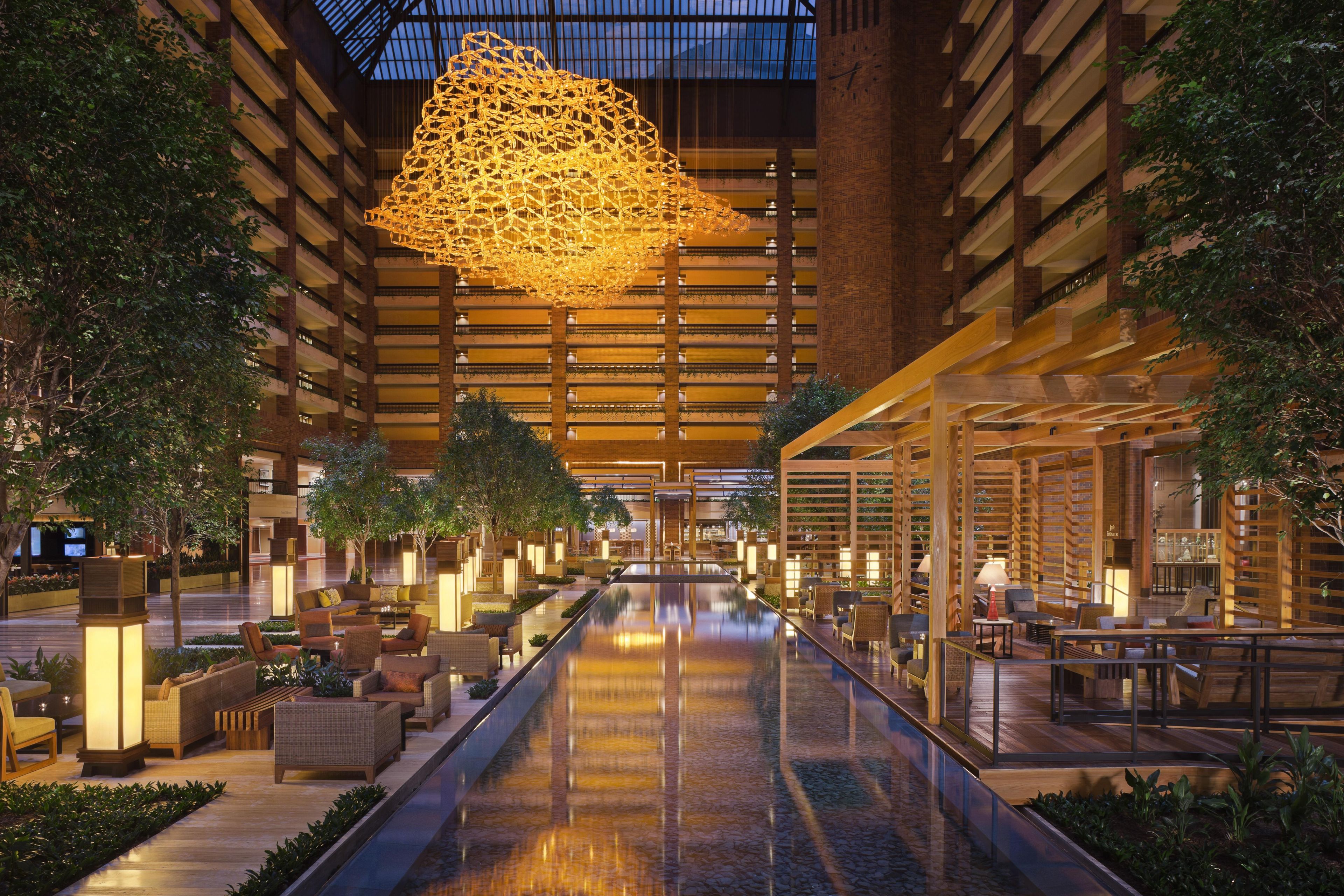 A spacious indoor atrium with a central water feature, seating areas, and a large hanging light fixture.
