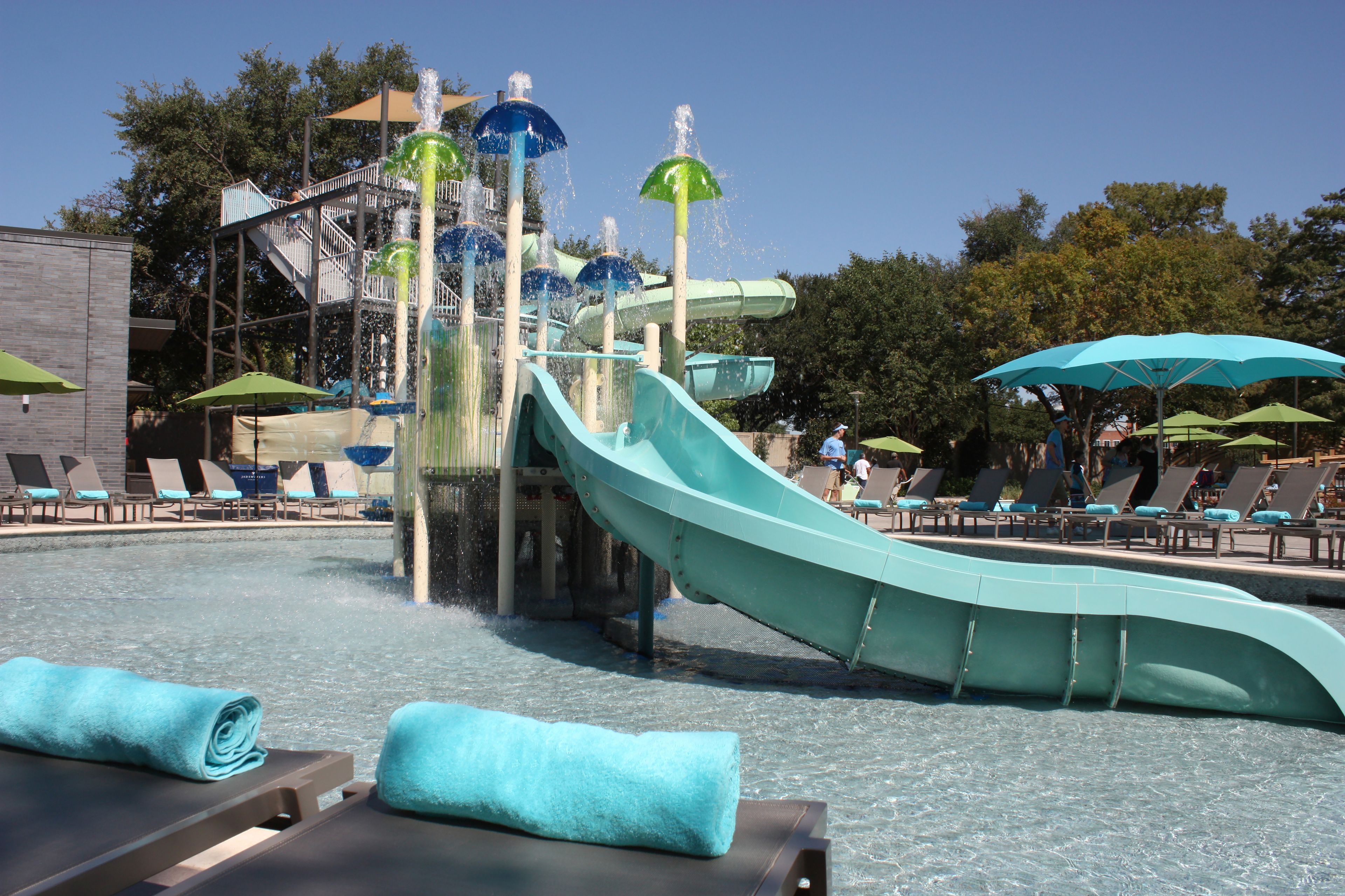 A water park with a large water slide, lounge chairs, and umbrellas.
