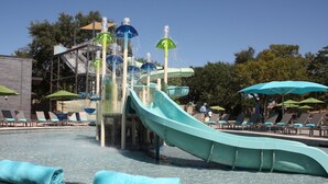 A water park with a large water slide, lounge chairs, and umbrellas.