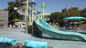 Een waterpark met een lange glijbaan, ligbedden en parasols.