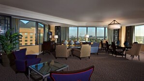 A hotel room with a large window, a seating area with a glass coffee table, and a view of the cityscape.