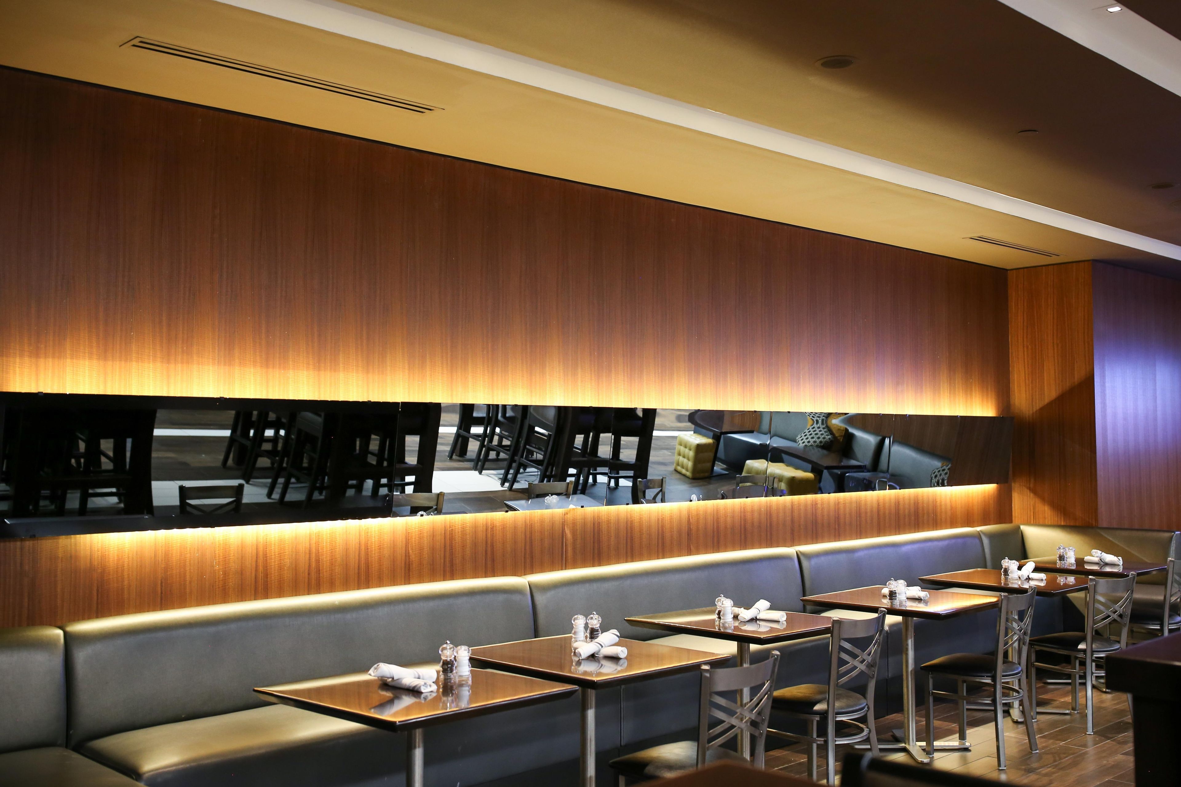 Un interior de restaurante con una barra larga, varias mesas y cabinas.