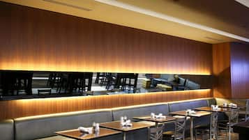 Un interior de restaurante con una barra larga, varias mesas y cabinas.