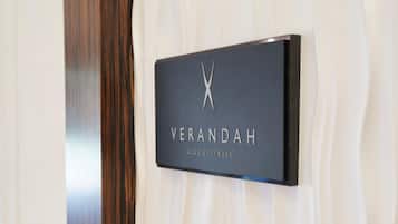 A black sign with the word 'VERANDAH' and the words 'CLUB & FITNESS' on a textured wall.