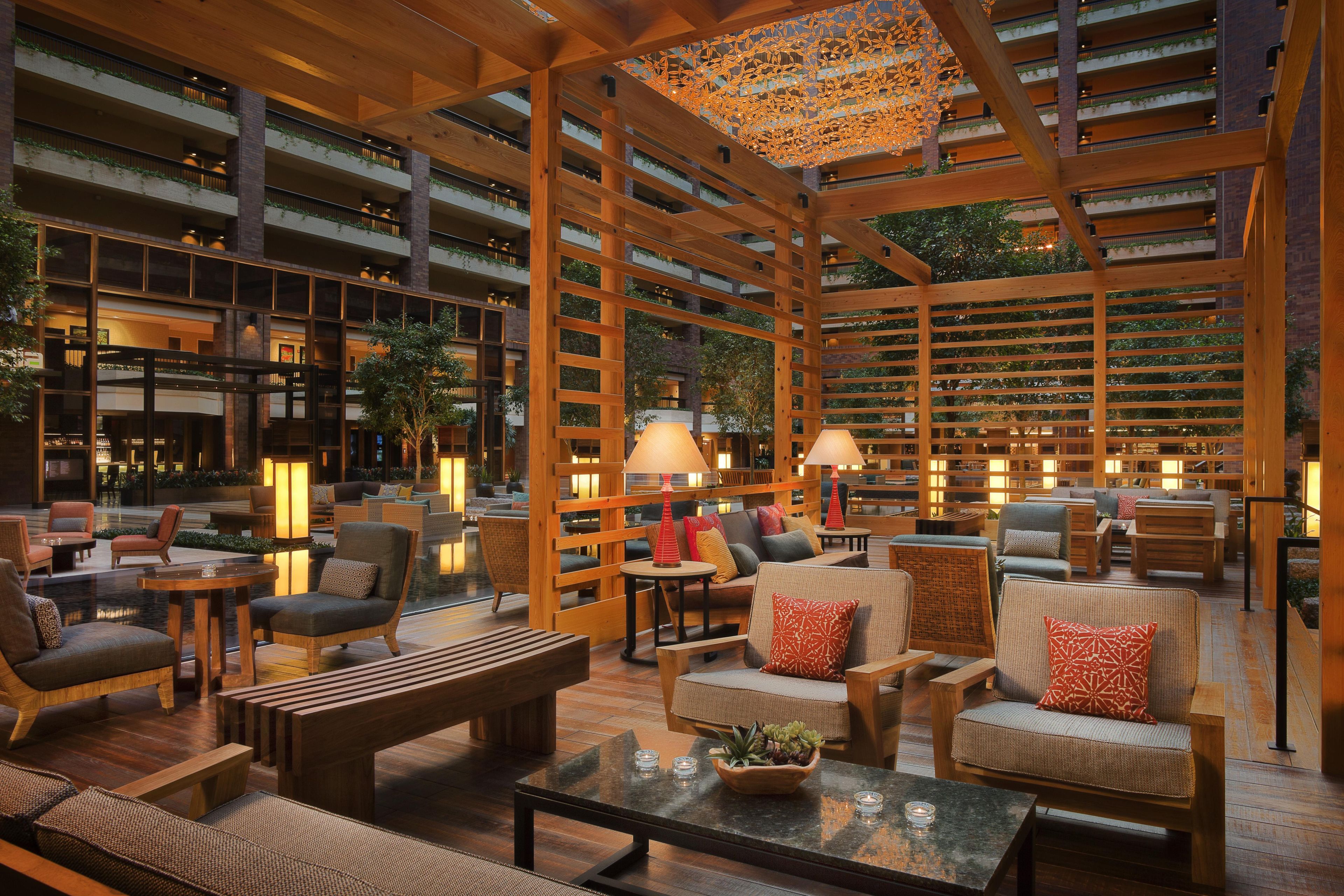 A spacious indoor area with multiple seating arrangements, wooden beams, and a ceiling with a decorative light fixture.