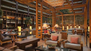 A spacious indoor area with multiple seating arrangements, wooden beams, and a ceiling with a decorative light fixture.