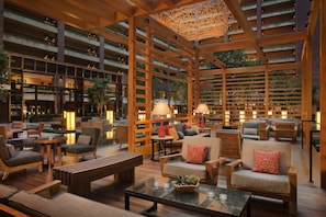 A spacious indoor area with multiple seating arrangements, wooden beams, and a ceiling with a decorative light fixture.
