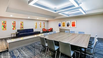 Un salón de conferencias con una larga mesa, sillas, un sofá y un mostrador de recepción.