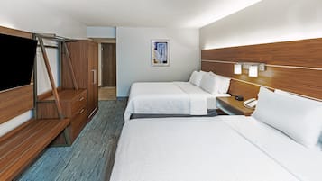 A hotel room with two beds, a TV, wooden wardrobe, and a painting on the wall.