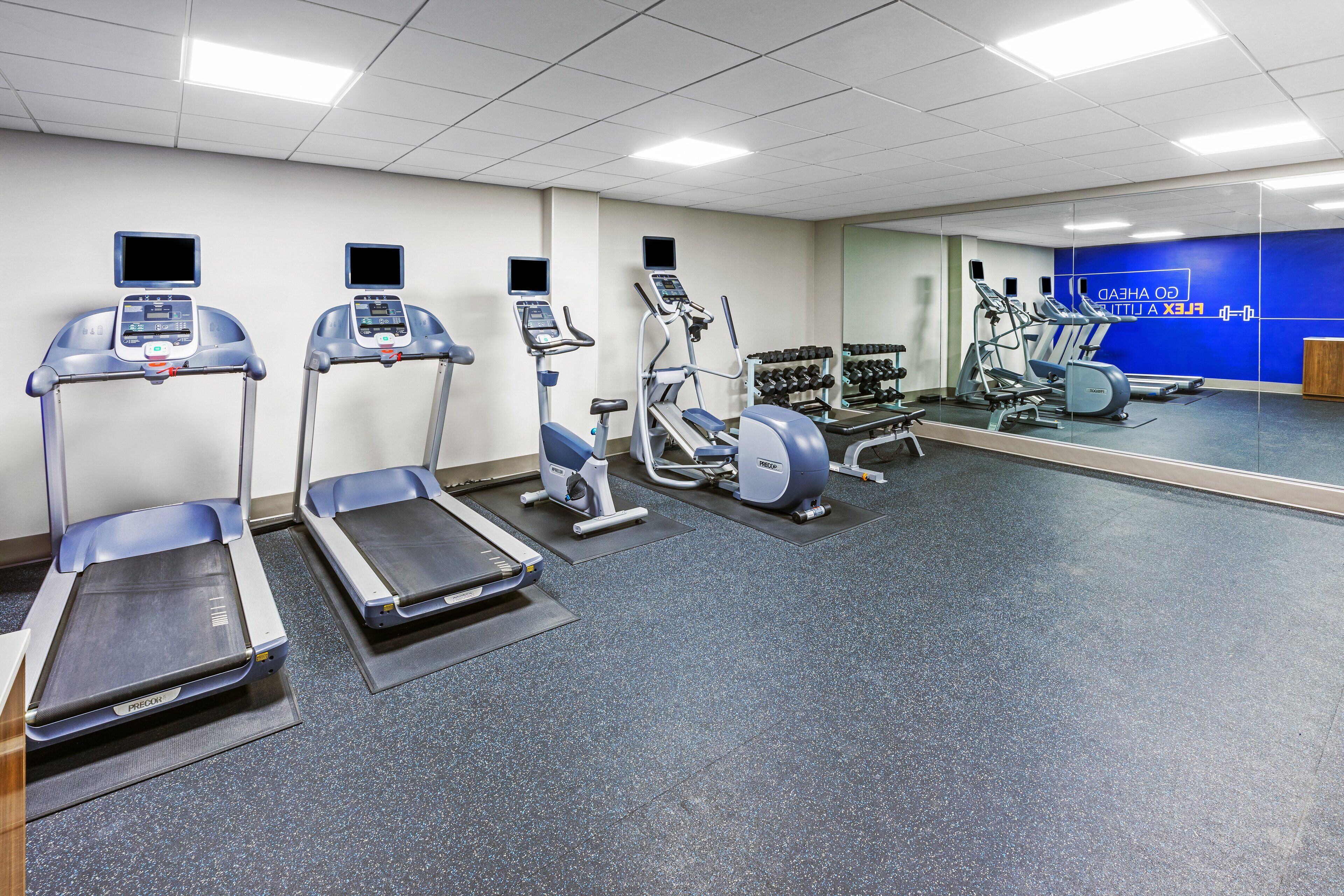 A gym with treadmills, elliptical machines, and weight benches.