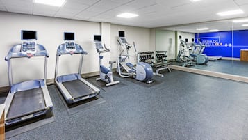 A gym with treadmills, elliptical machines, and weight benches.