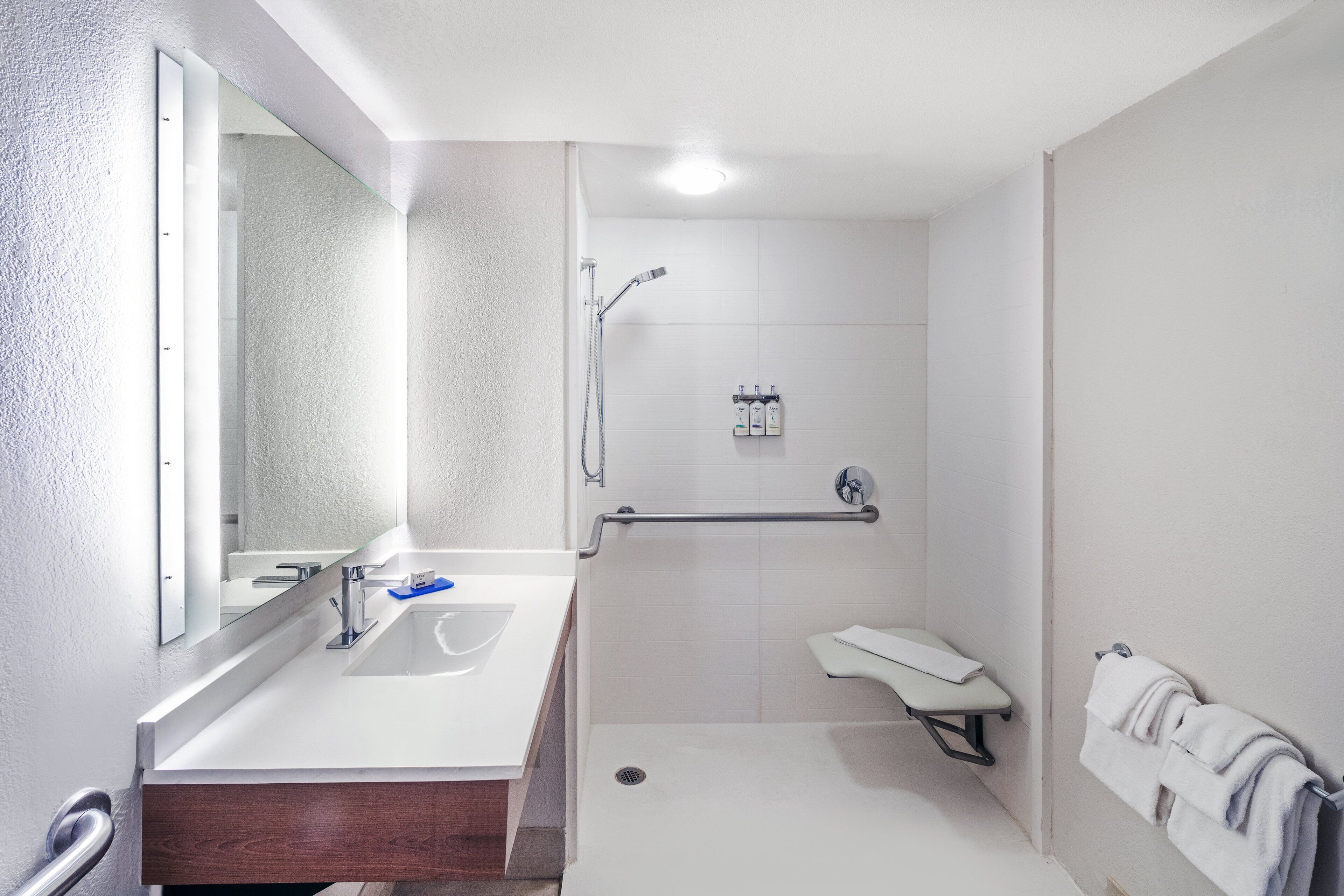 A modern bathroom with a white sink, mirror, and shower area.