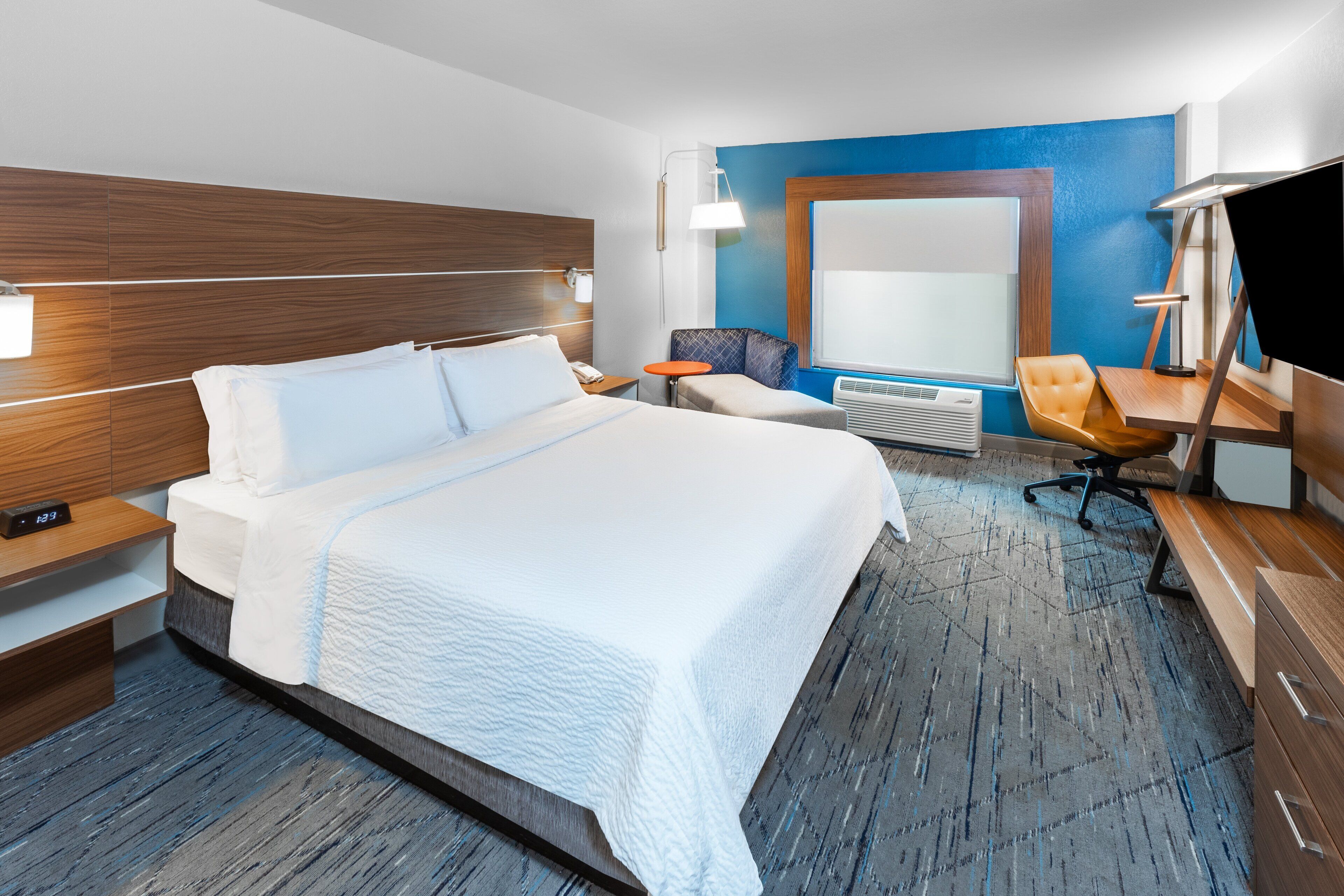 Una habitación de hotel con una cama grande, un escritorio, una silla, un televisor y una ventana.