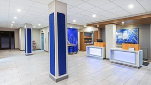 A modern lobby with a reception desk, a blue accent wall, and a reception area with a counter and shelves.