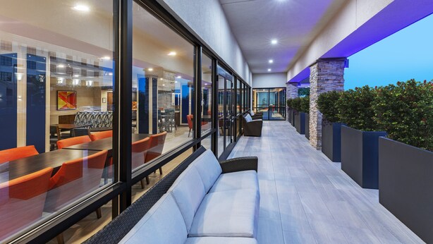 A modern indoor patio area with glass walls, seating, and a view of the outside.