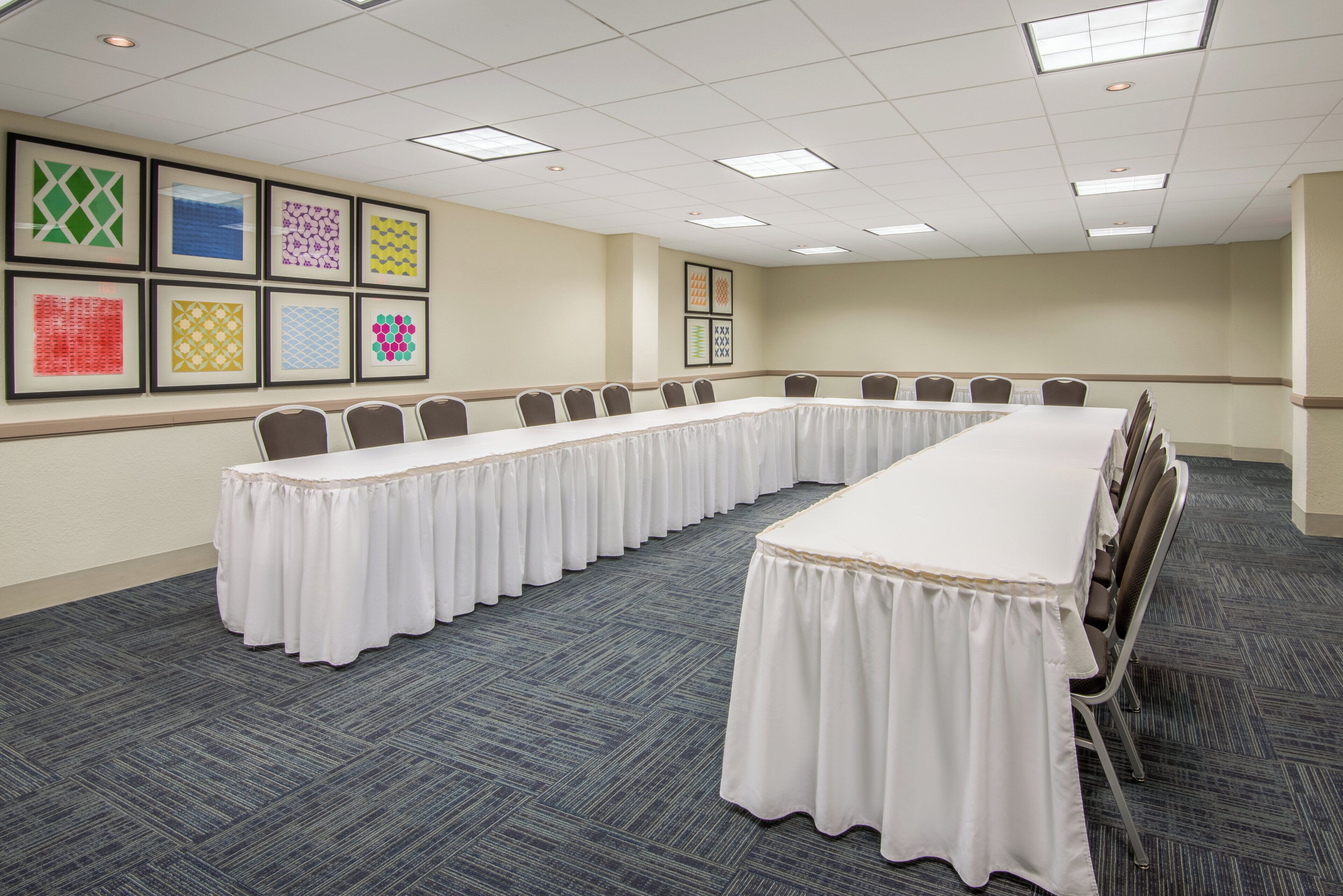 A conference room with a long table, chairs, and framed artwork on the walls.