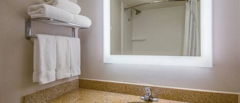 A bathroom with a sink, mirror, towel rack, and shower.