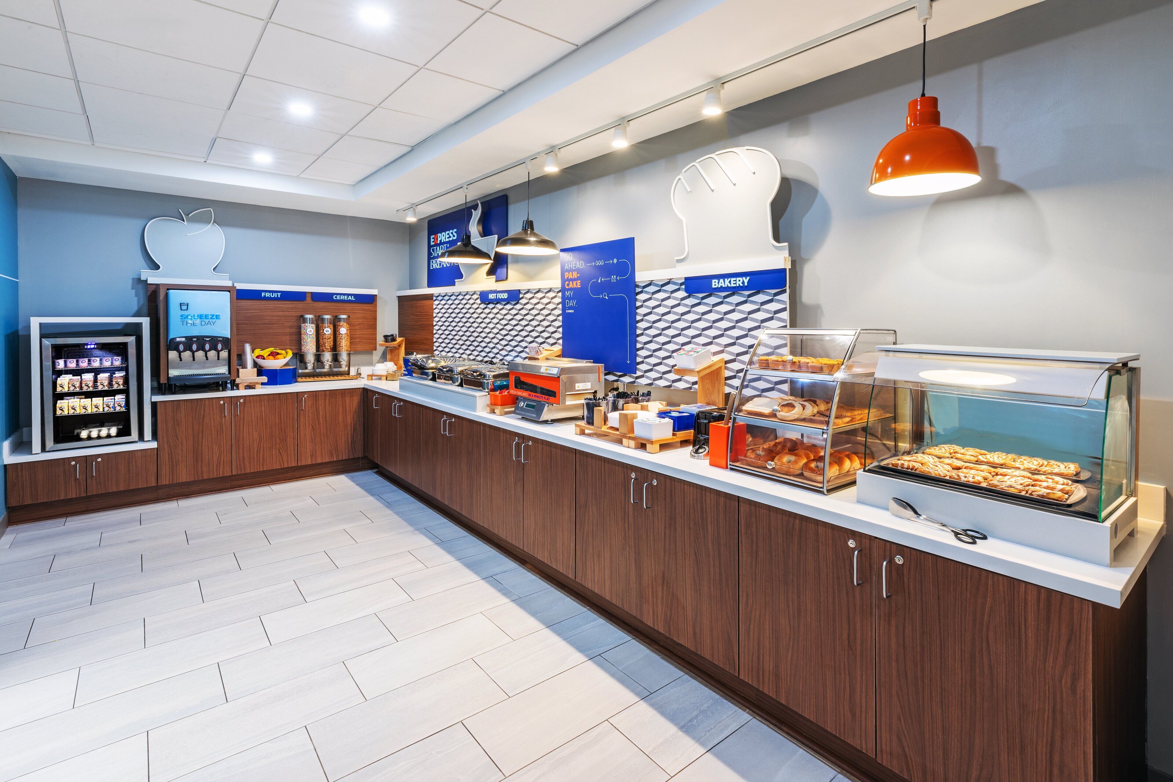 A modern breakfast bar with a variety of food options, including a bakery display and a coffee machine.