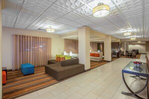A hotel room with a sofa, a small table, and a dining area with chairs.