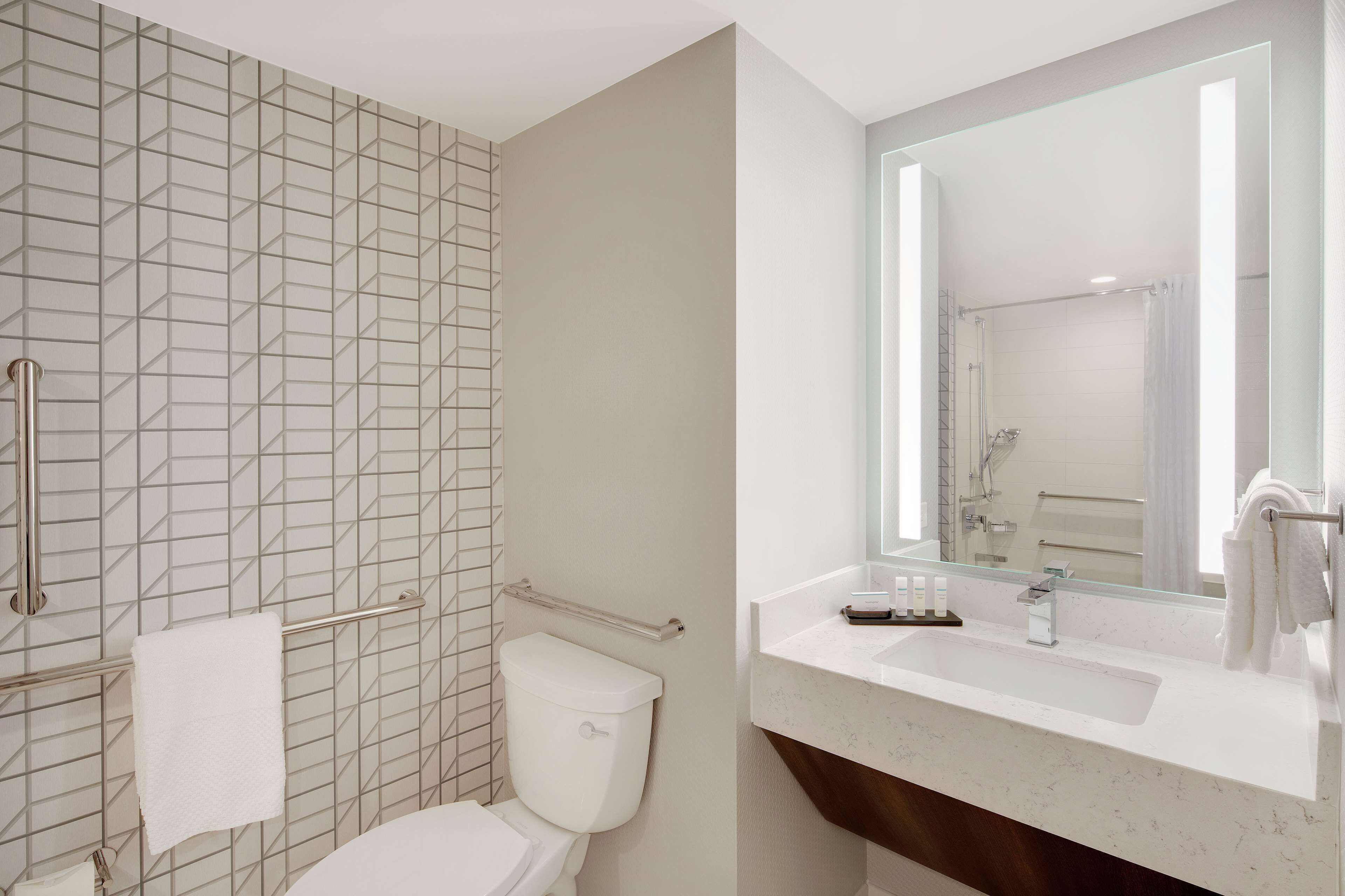 Ein modernes Badezimmer mit Toilette, Duschbereich und Waschtisch mit Spiegel.
