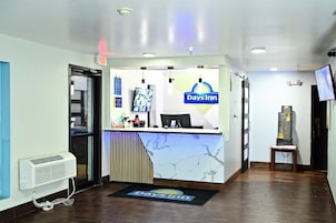 A reception area with a Days Inn sign, a reception desk, a computer, and a small table with a chair.