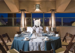Una elegante mesa de comedor dispuesta para seis personas, con manteles blancos, caminos de mesa de encaje y centros de mesa con velas.