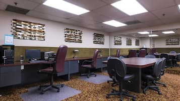 A conference room with a long table, multiple chairs, and a carpeted floor.