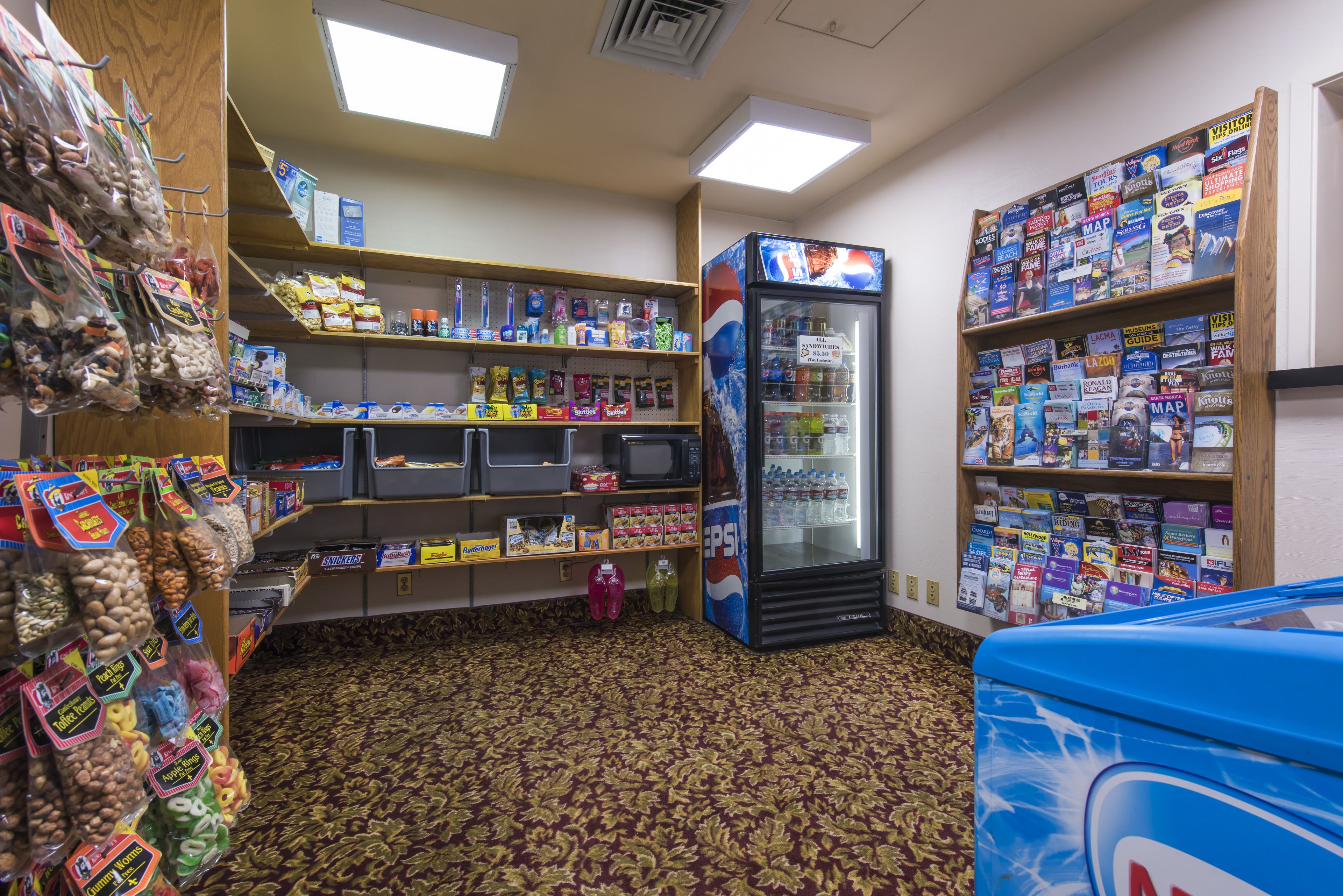 A convenience store with shelves stocked with snacks, beverages, and travel books.
