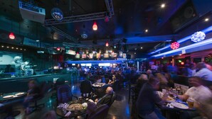 A busy bar with a stage for live performances, tables and chairs for dining, and a DJ booth. - Grand Vista Hotel (Simi Valley)