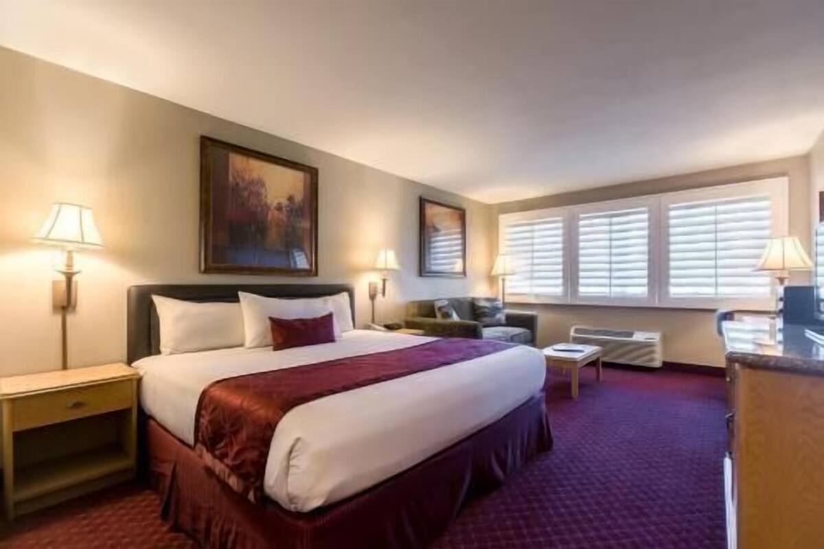 A hotel room with a large bed, two bedside tables, a desk, and a chair.
