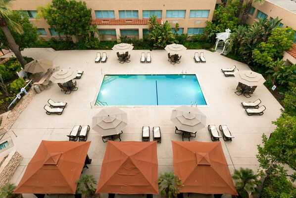 An outdoor swimming pool with lounge chairs and umbrellas arranged around it. - Grand Vista Hotel (Simi Valley)