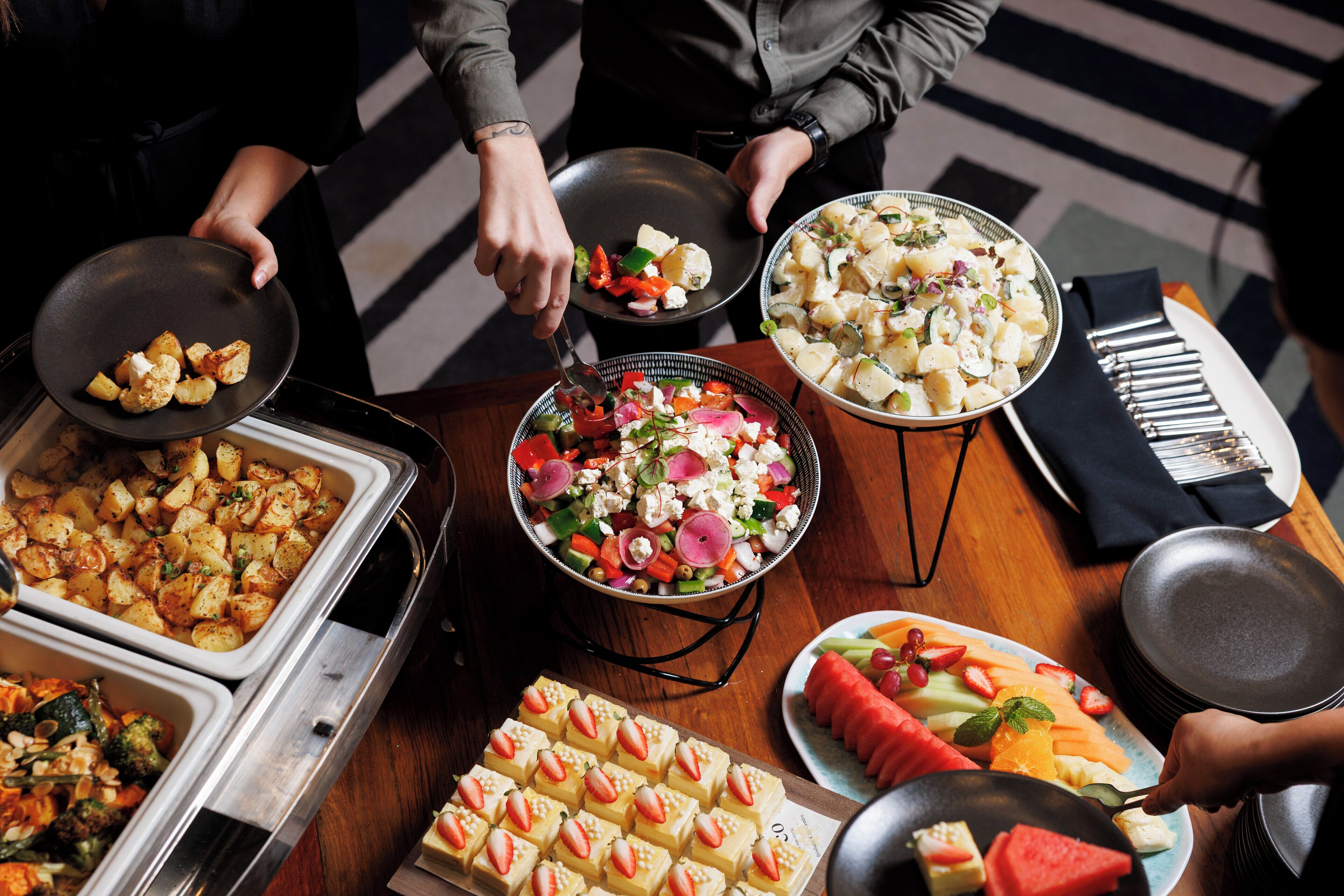A buffet with various dishes including salads, fruits, and appetizers.