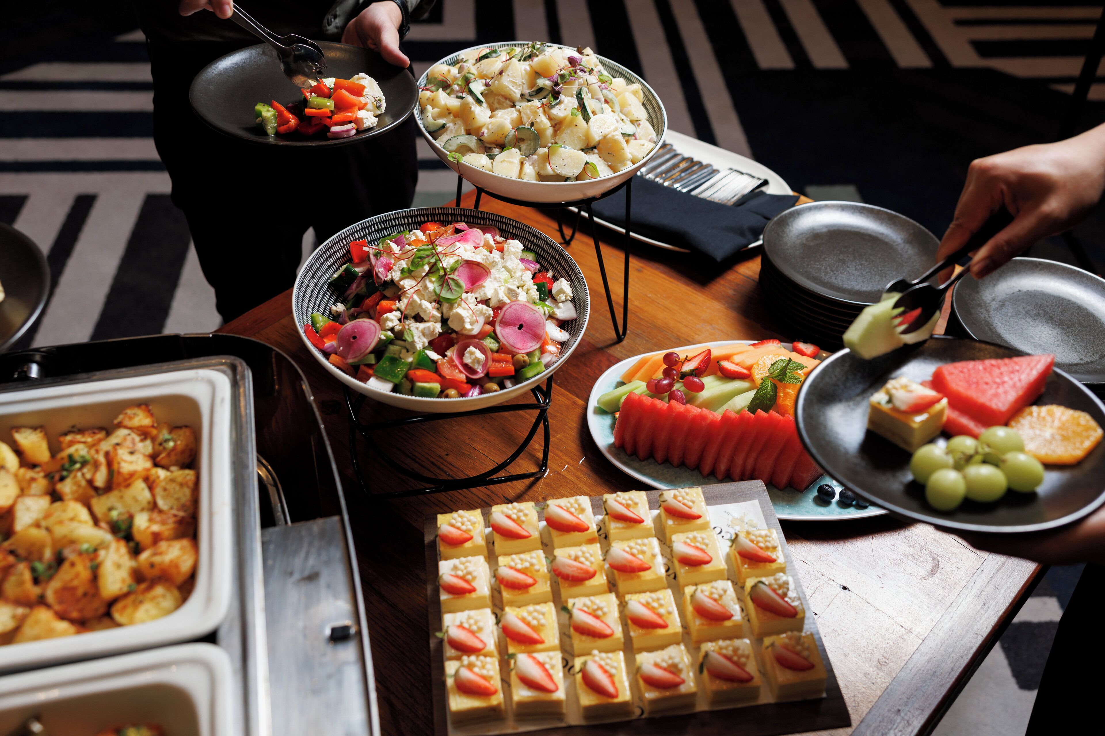 Una mesa de buffet con diversos platos, como ensaladas, frutas y postres.