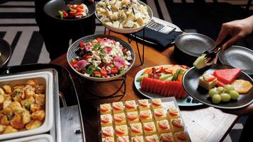 Una mesa de buffet con diversos platos, como ensaladas, frutas y postres.